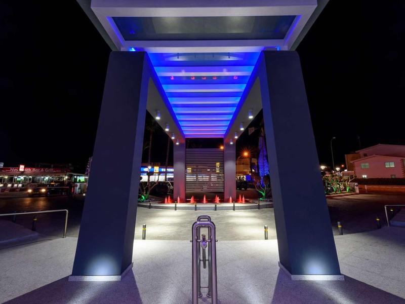 Blauwe LED-verlichting onder een moderne ingang bij nacht.