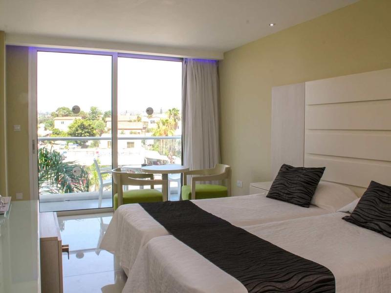 Moderne hotelkamer met tweepersoonsbed, balkon en uitzicht op palmbomen en water