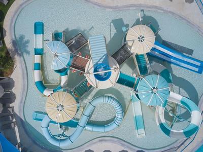 Luftaufnahme eines Wasserparks mit mehreren Wasserrutschen und runden Schutzhütten neben einem Pool.