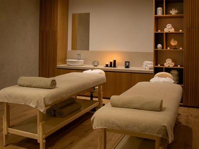 Ein ruhiger Spa-Raum mit zwei Massageliegen und sanfter Beleuchtung.