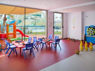 Bunter Kinderspielraum mit Tischen, Stühlen, Rutsche und Bowlingbahn in einem Hotel.