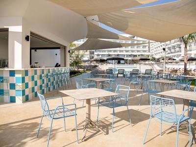 Freiluft-Sitzbereich mit blauen Stühlen und Tischen neben einem Pool in einem Hotel.