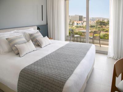 Modernes Hotelzimmer mit großem Bett und Balkon mit Stadtblick