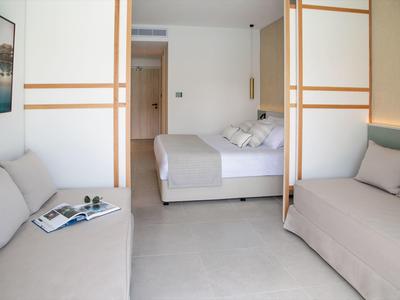 Modernes Hotelzimmer mit zwei Sofas und einem Bett in neutralen Farben