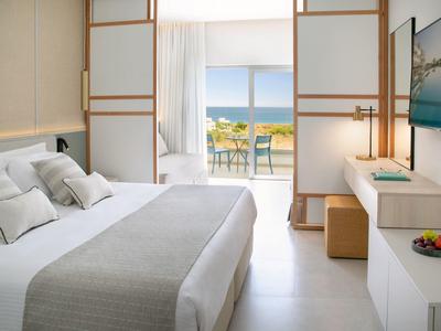 Modernes Hotelzimmer mit großem Bett, Schiebetüren und Balkon mit Meerblick