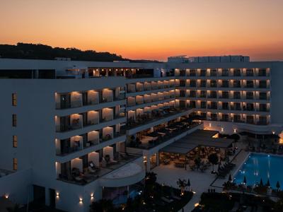 Hotelkomplex mit beleuchtetem Pool und Gästen bei Sonnenuntergang