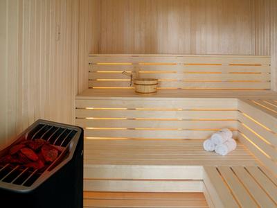 Helle Holzsauna mit mehrstufigen Bänken, einem Saunaofen und weißen Handtüchern.