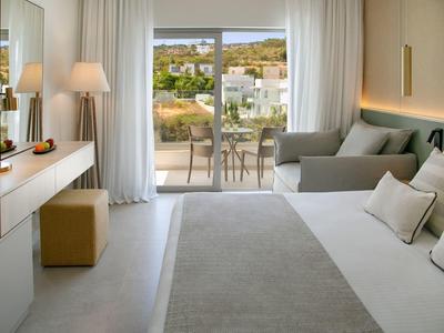 Modernes Hotelzimmer mit King-Size-Bett, Sofa und Terrasse mit Aussicht.