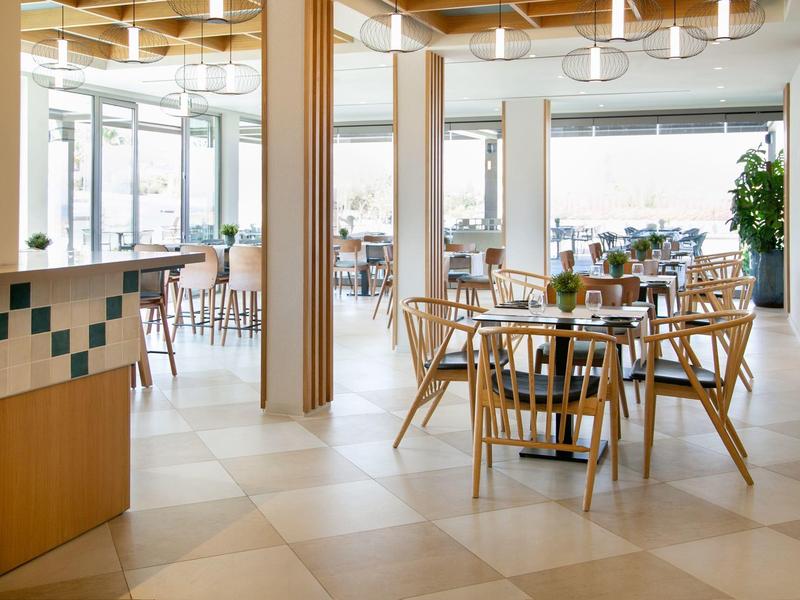 Helles, modernes Restaurant mit Holzstühlen und großen Fenstern für viel Tageslicht.