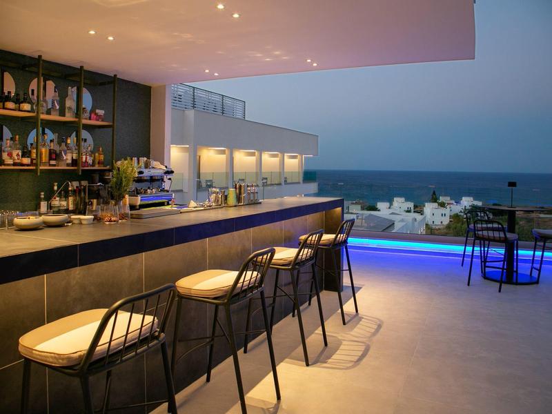 Elegante Hotelbar mit Blick auf das Meer bei Dämmerung und modernen Sitzgelegenheiten.