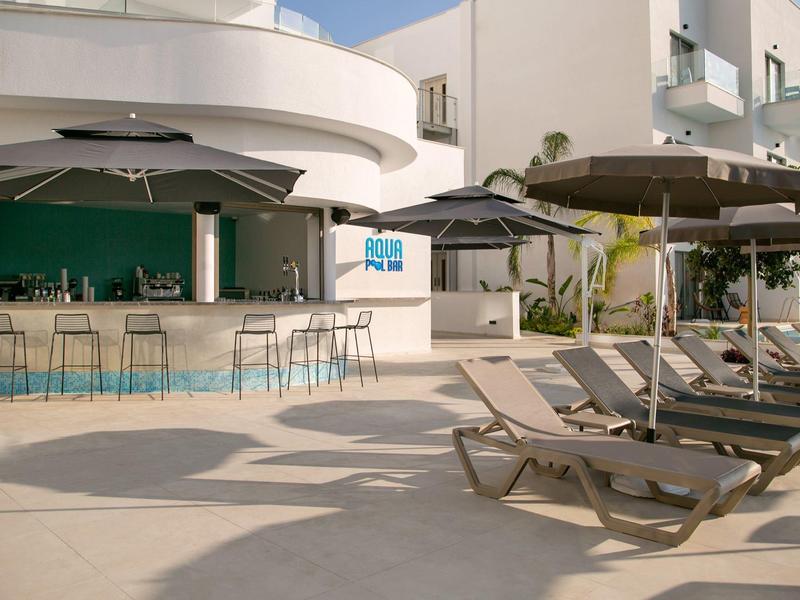 Moderner Hotelpoolbereich mit Bar, Stühlen und Liegestühlen unter Sonnenschirmen.