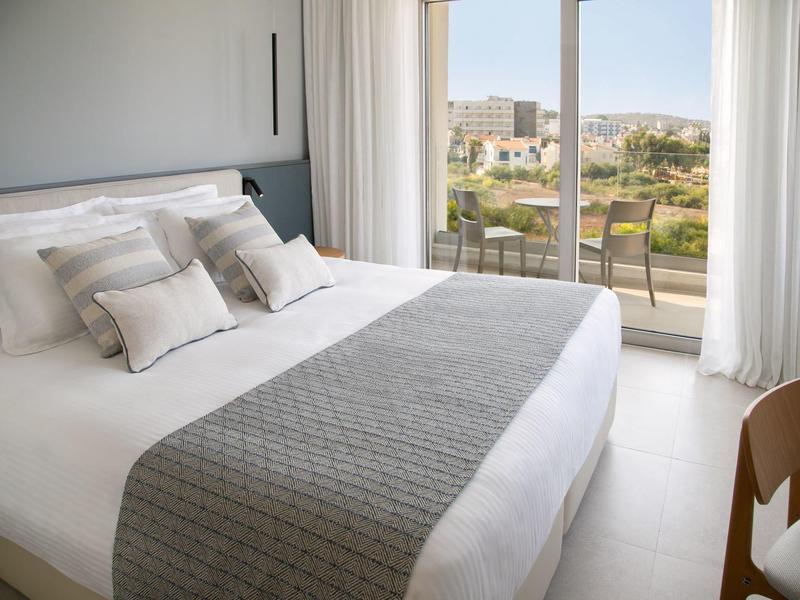 Modernes Hotelzimmer mit großem Bett und Balkon mit Stadtblick