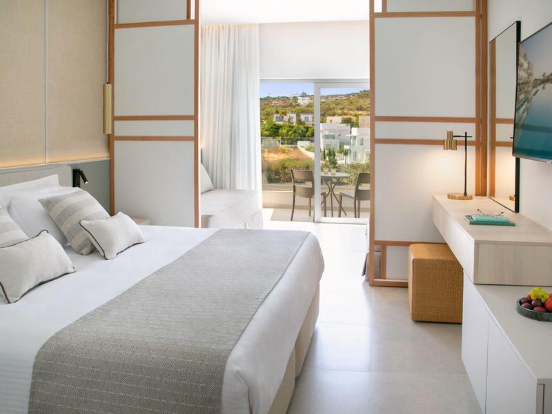 Modernes Hotelzimmer mit großem Bett, Schiebetüren und Balkon mit Aussicht.