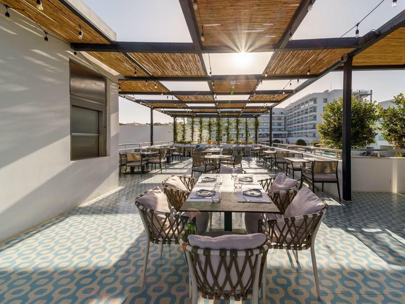 Moderne Außenterrasse mit gedeckten Tischen und geflochtenen Stühlen in einem Hotel.
