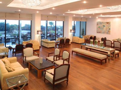 Großer Lounge-Bereich mit bequemen Sesseln, Sofas und breiten Fenstern mit Blick auf die Natur.