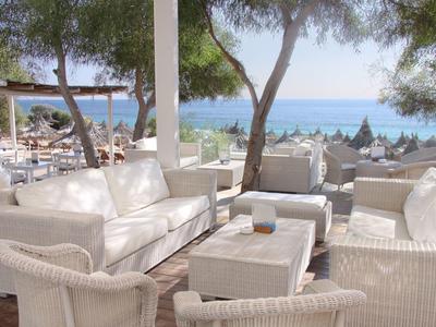 Weißes Lounge-Set auf einer Terrasse mit Meerblick und Bäumen im Hintergrund.