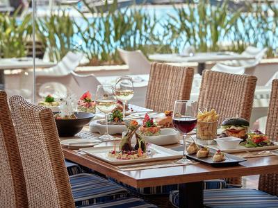 Ein gedeckter Tisch mit Speisen und Wein auf der Terrasse eines Restaurants mit Blick aufs Wasser.