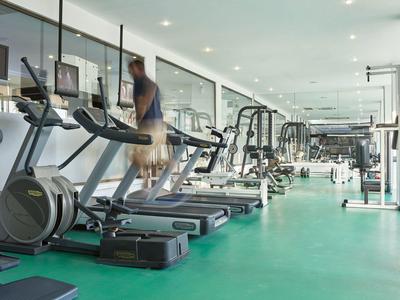 Moderner Fitnessraum mit Laufbändern, Geräten und großen Fenstern für Tageslicht.