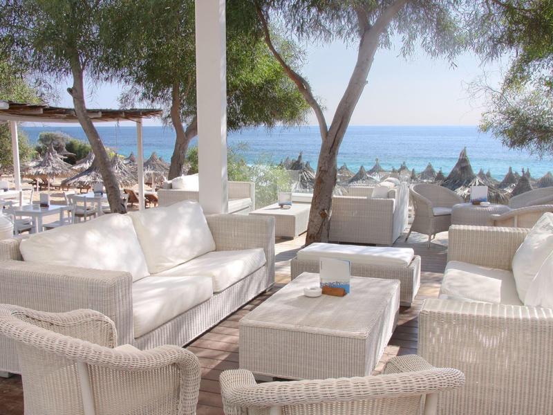 Weißes Lounge-Set auf einer Terrasse mit Meerblick und Bäumen im Hintergrund.