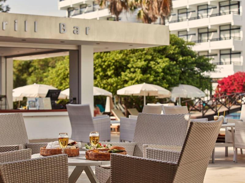 Outdoor-Sitzbereich einer Hotelbar mit Tischen, Stühlen und Sonnenschirmen bei Tageslicht