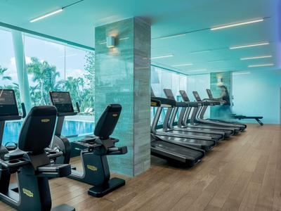 Moderner Fitnessraum mit Laufbändern und Fahrradergometern, großem Fenster und Holzboden.