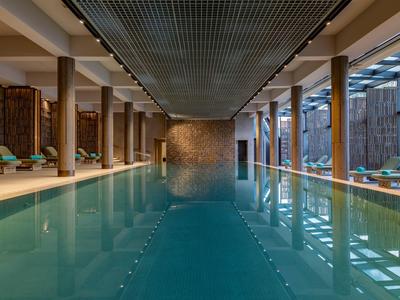 Großes Hallenbad mit Säulen und Tageslicht durch große Fenster in einem Hotel.