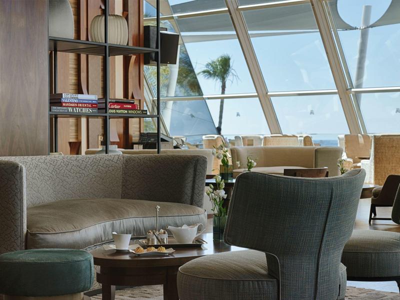 Pohodlná odpočinková zóna s pohovkami a křesly před velkými okny s výhledem na moře.