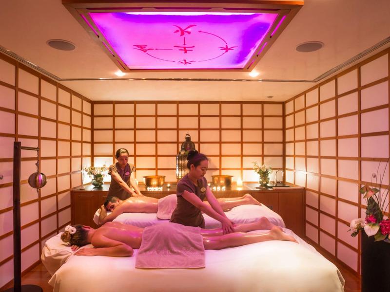 Dvě ženy si užívají relaxační masáž v místnosti lázní s tlumeným osvětlením.