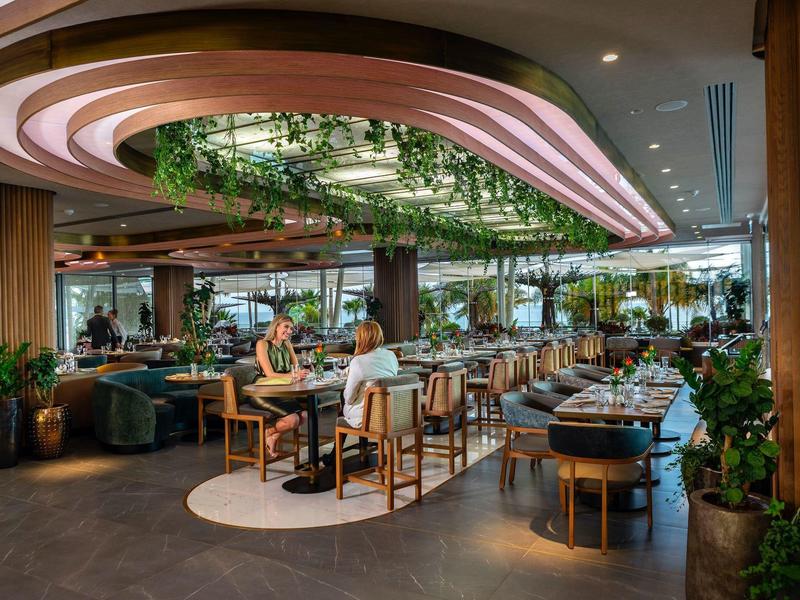 Moderní hotelová restaurace se stylovým osvětlením, závěsnými rostlinami a útulnými posezeními.