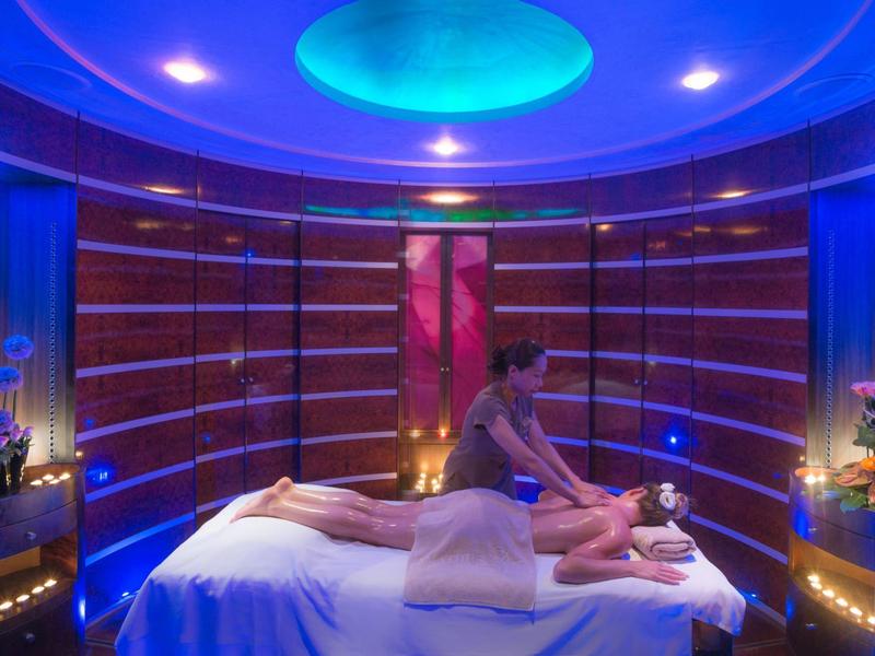 Osoba dostávající masáž v luxusním spa s modrým osvětlením a uklidňující atmosférou.