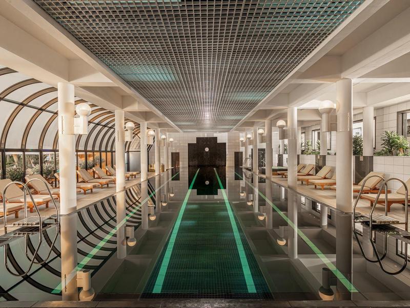 Luxusní vnitřní bazén s posezením a jemným osvětlením v hotelu.