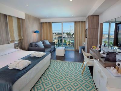 Modernes Hotelzimmer mit Doppelbett, Sitzbereich, großem Fenster und Fernseher, hell und geräumig.