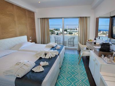Modern hotel room with double bed, balcony with sea view, and TV