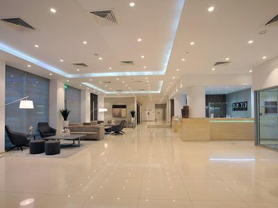 Großer, heller Raum mit glänzendem Boden, moderner Möblierung und Deckenbeleuchtung in Weiß und Beige.