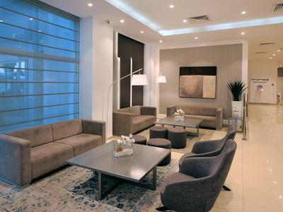 Modern hotel lounge area with seating groups, tables, and decorative lighting.