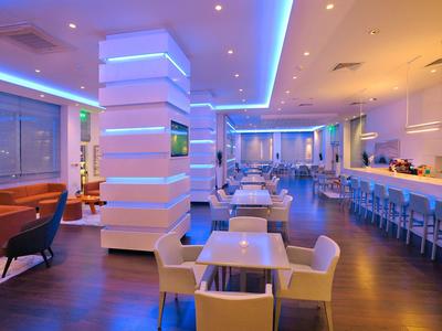 Modern hotel restaurant with stylish lighting and seating areas with chairs and tables.
