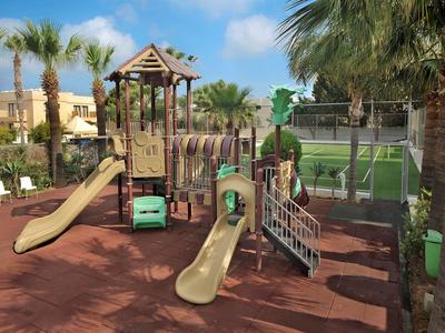 Kinderspielplatz mit Rutschen, Klettergerüst und weichem Bodenbelag, umgeben von Palmen.