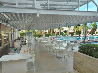 Modern outdoor hotel area with tables, chairs, and a view of the pool