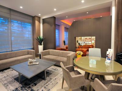 Moderner Wohnraum mit großen Fenstern, grauen Sofas, rundem Tisch und warmem Licht innen.