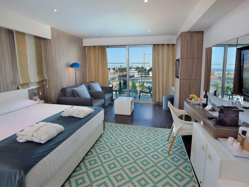 Modernes Hotelzimmer mit Doppelbett, Sitzbereich, großem Fenster und Fernseher, hell und geräumig.