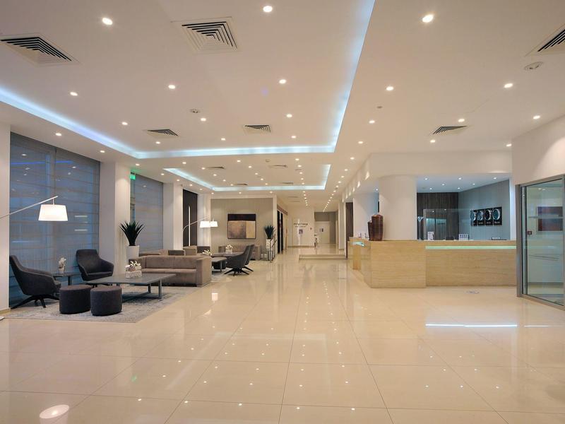 Großer, heller Raum mit glänzendem Boden, moderner Möblierung und Deckenbeleuchtung in Weiß und Beige.