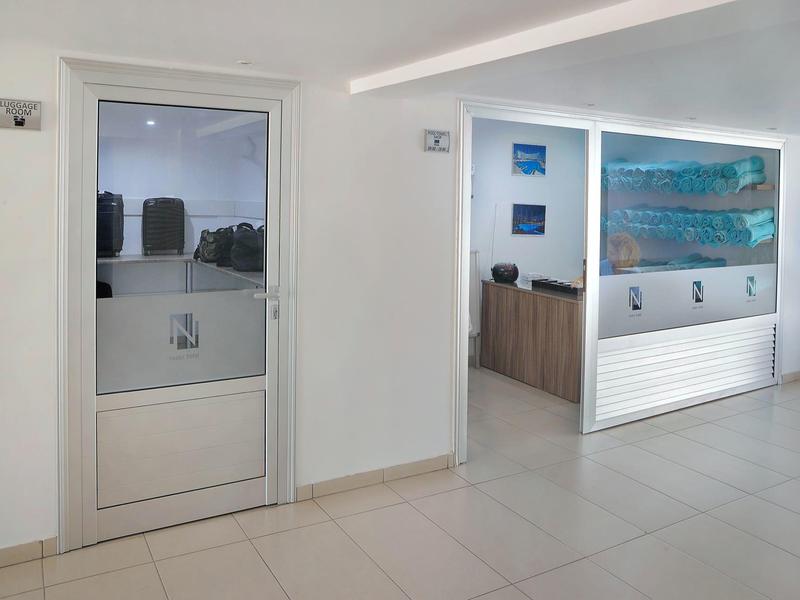 Moderner, heller Raum mit weißem Boden, Glastür und Empfangstresen mit Kunst an der Wand.