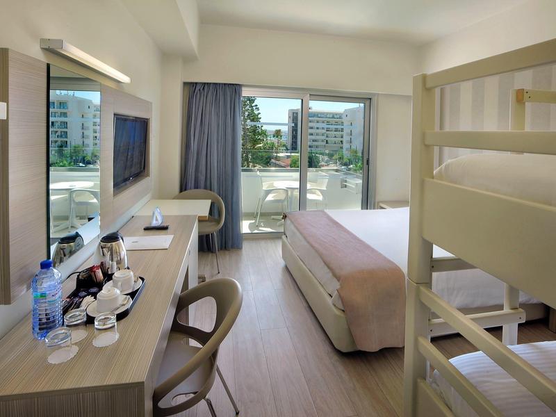 Modernes Hotelzimmer mit Etagenbett, großem Fenster, Schreibtisch und urbaner Aussicht.