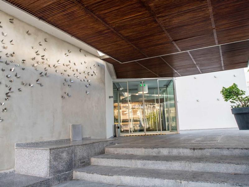 Moderner Hauseingang mit Treppen, Glasfront, Holzdecke und Wanddekoration aus Metallvögeln.