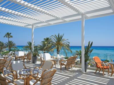 Offener Hotelterrassenbereich mit Stühlen und Tischen mit Blick auf das Meer.