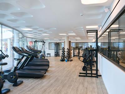 Moderner Fitnessraum mit Laufbändern, Gewichten und großem Fenster in hellem Ambiente.