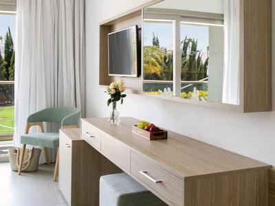 Heller Hotelzimmerbereich mit Holzschreibtisch, Stuhl und großem Wandspiegel.