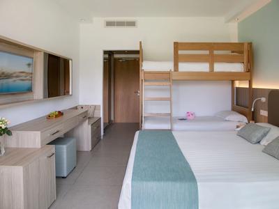 Modernes Hotelzimmer mit Doppelbett, Etagenbett und Schreibtisch in hellem Design.