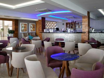 Moderne Hotelbar mit stilvollen Stühlen und indirekter blauer Beleuchtung an der Decke.