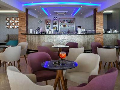 Barbereich eines Hotels mit moderner Beleuchtung und gemütlichen Sesseln um kleine Tische.
